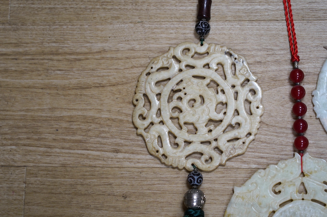 Four large Chinese carved bowenite jade discs, largest diameter 19cm, with tassel and bead wall hangings. Condition - fair to good